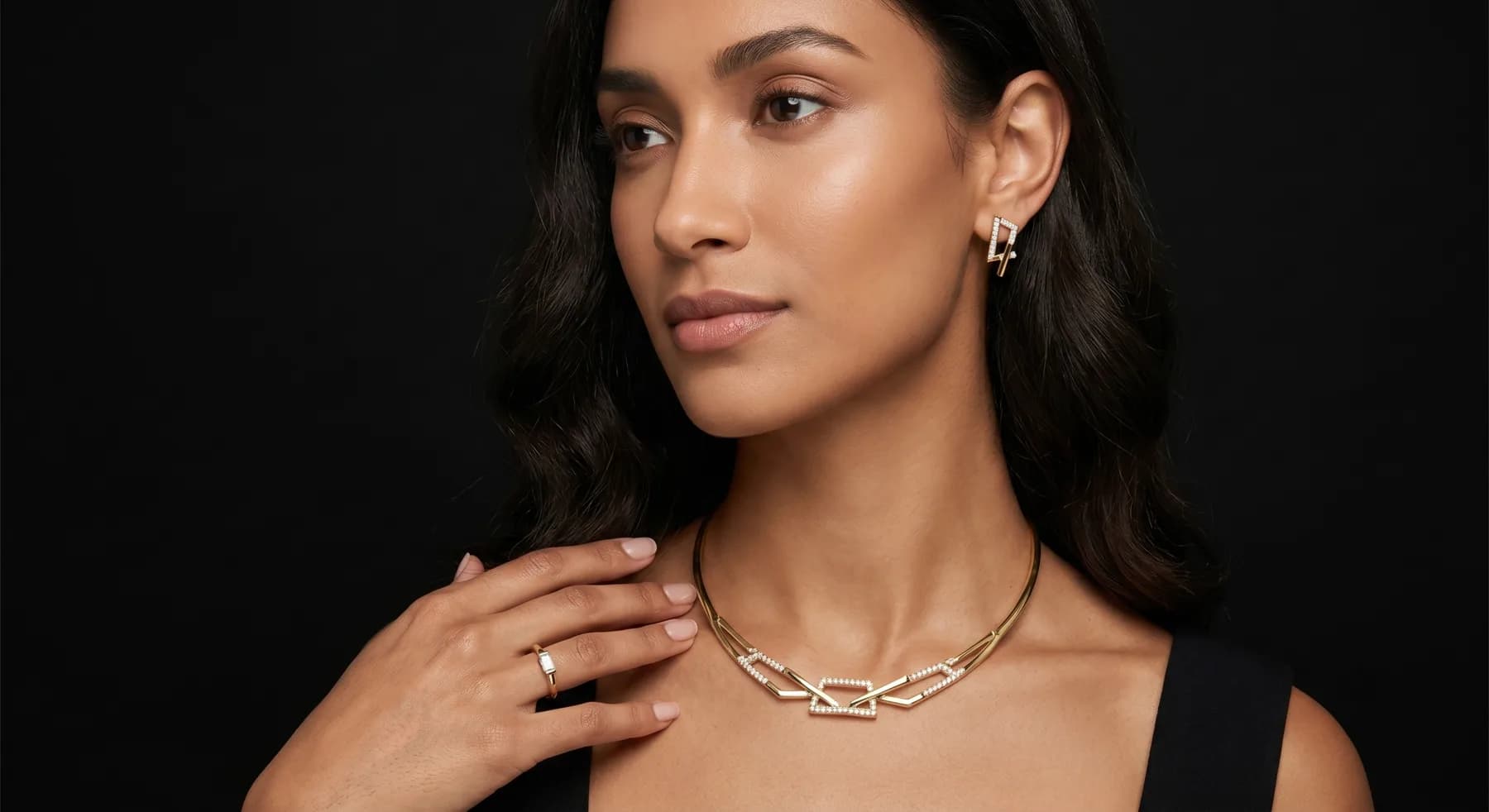 A model wearing a 7MARK gold link necklace, earrings, and ring