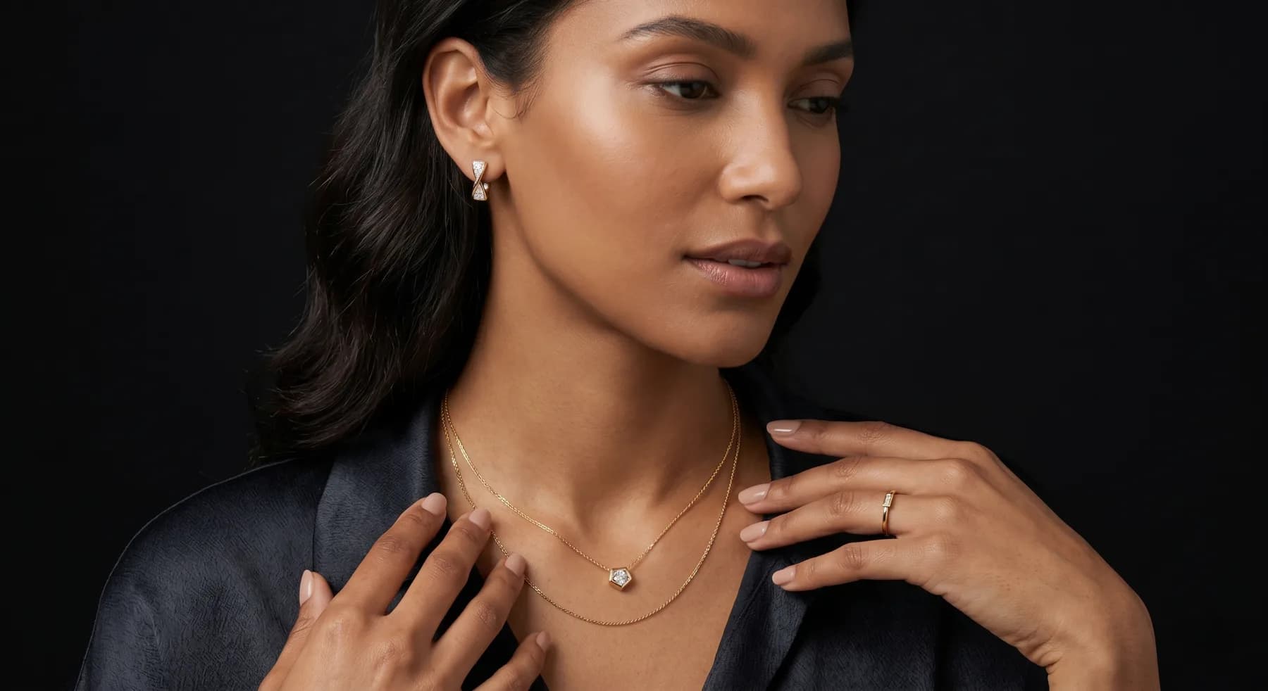 A model wearing a delicate layered 7MARK gold necklace and solitaire pendant